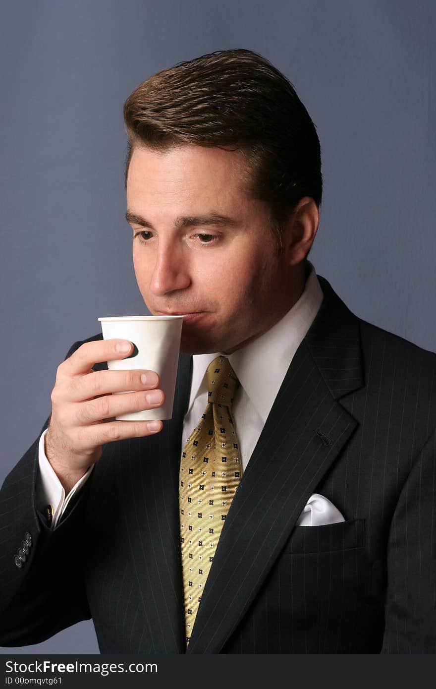 Businessman sips cup of coffee on blue background. Businessman sips cup of coffee on blue background