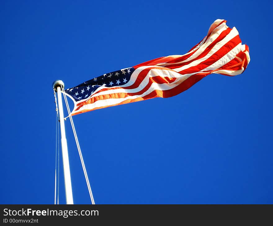 The American Flag waving proudly in the wind tethered to a flag pole. The American Flag waving proudly in the wind tethered to a flag pole.