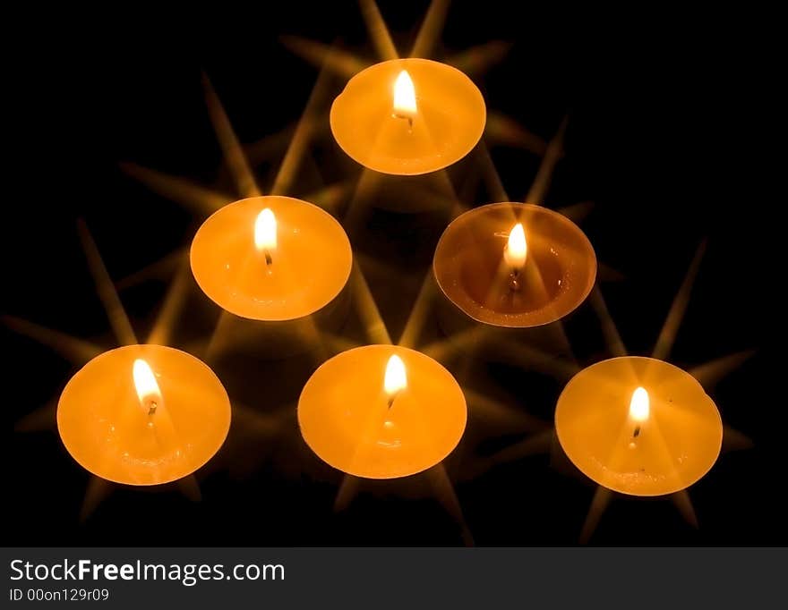 A group of six burning candles on the black background. A group of six burning candles on the black background