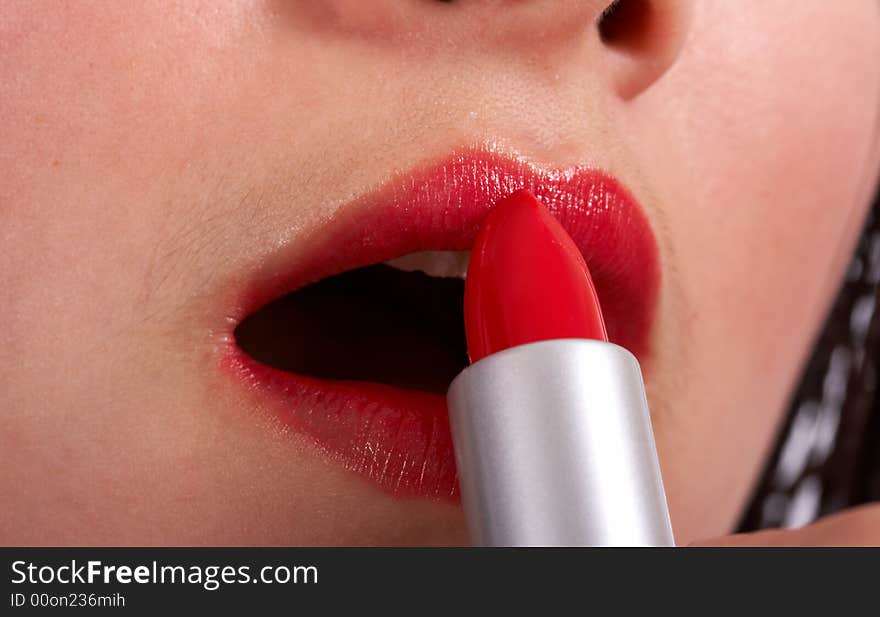 Young beautiful woman applying a red lipstick