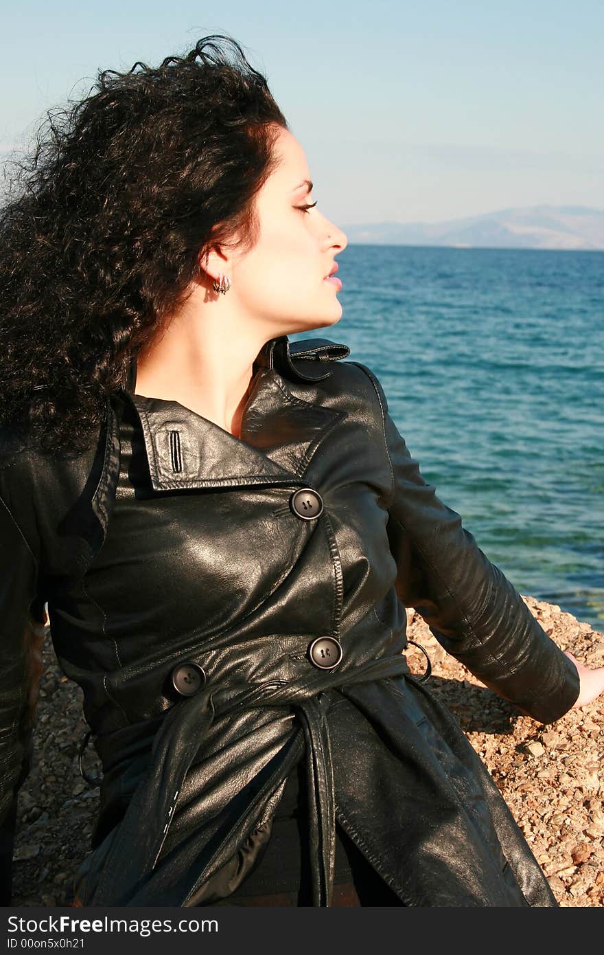 A young woman in leather jacket by the sea