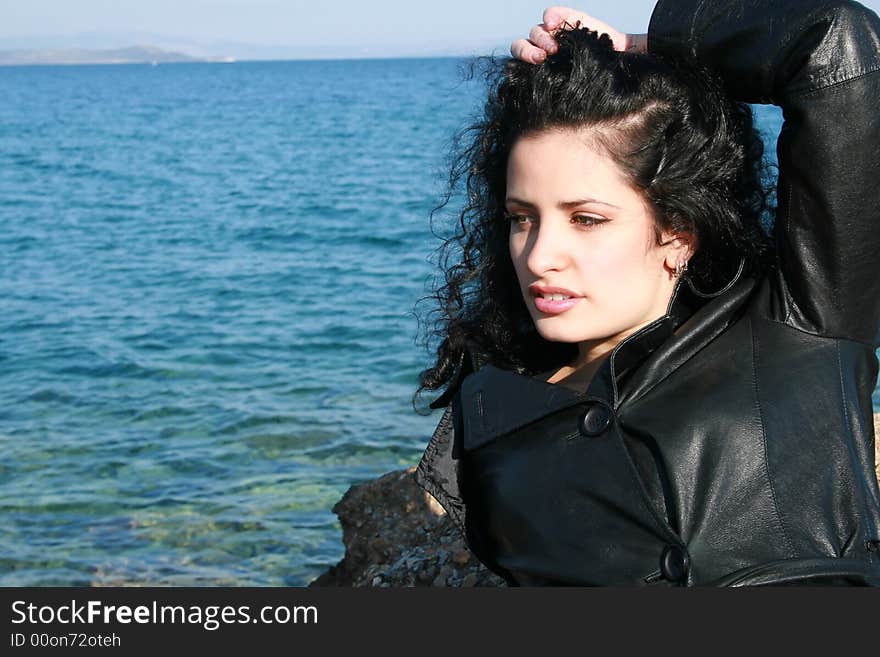 A young woman in leather jacket by the sea