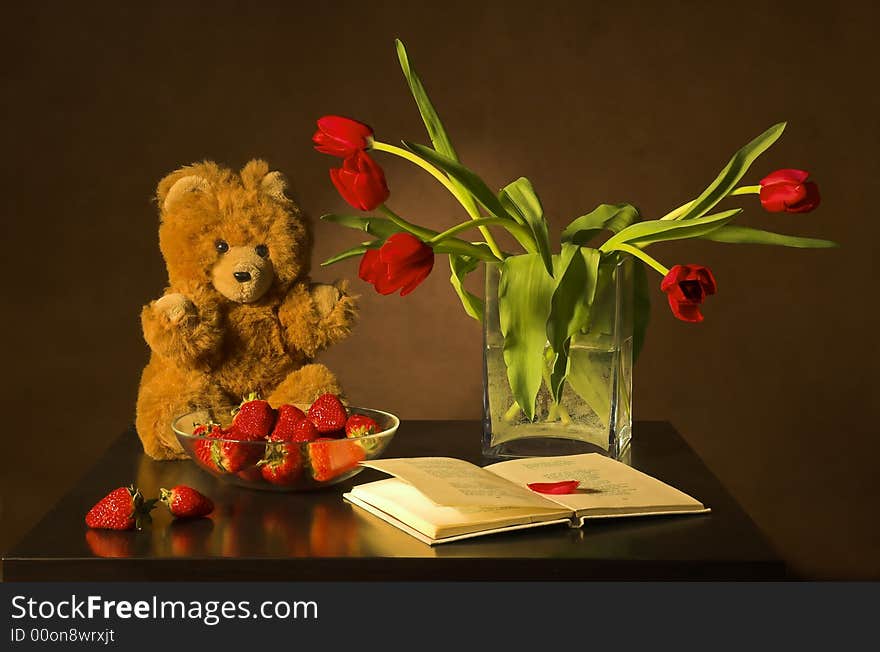 Still-life with tulips, the book and a strawberry on a dark background. Still-life with tulips, the book and a strawberry on a dark background