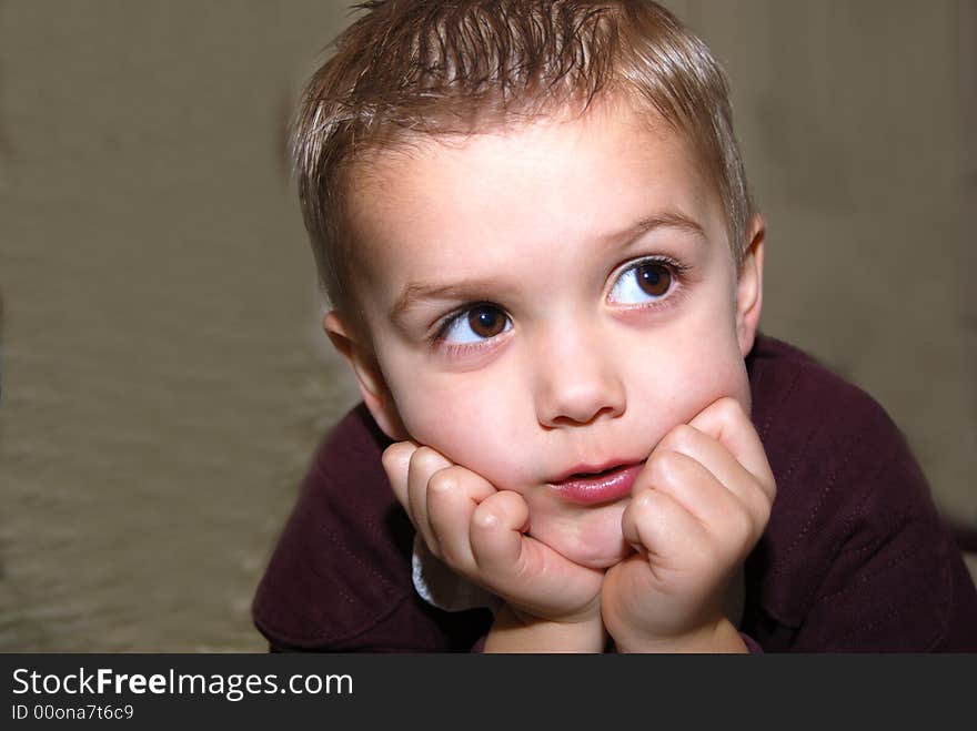 Boy posing chin on hands against muslin background sdof. Boy posing chin on hands against muslin background sdof