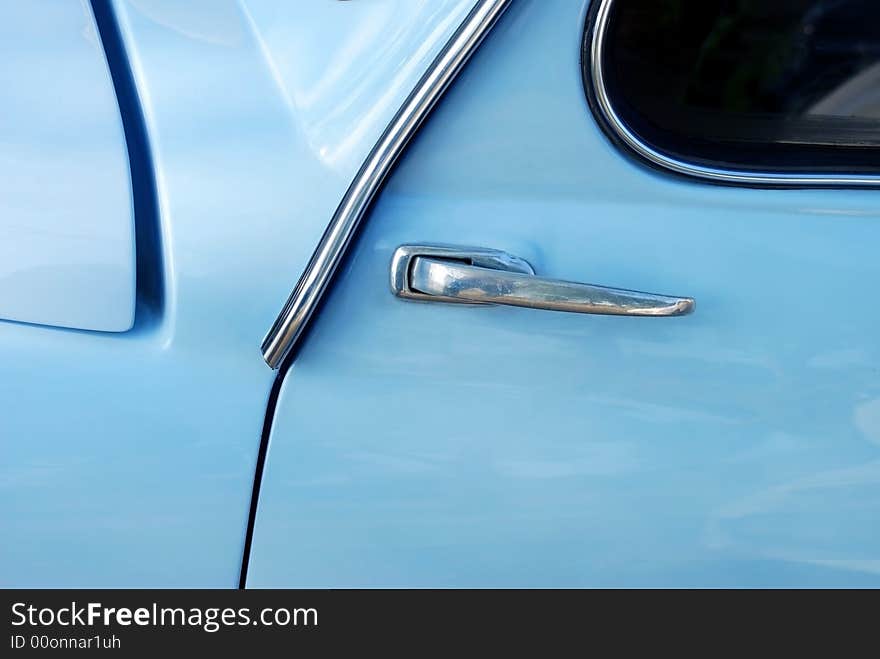 Detail image of the door handle of a light blue Fiat 600. Detail image of the door handle of a light blue Fiat 600