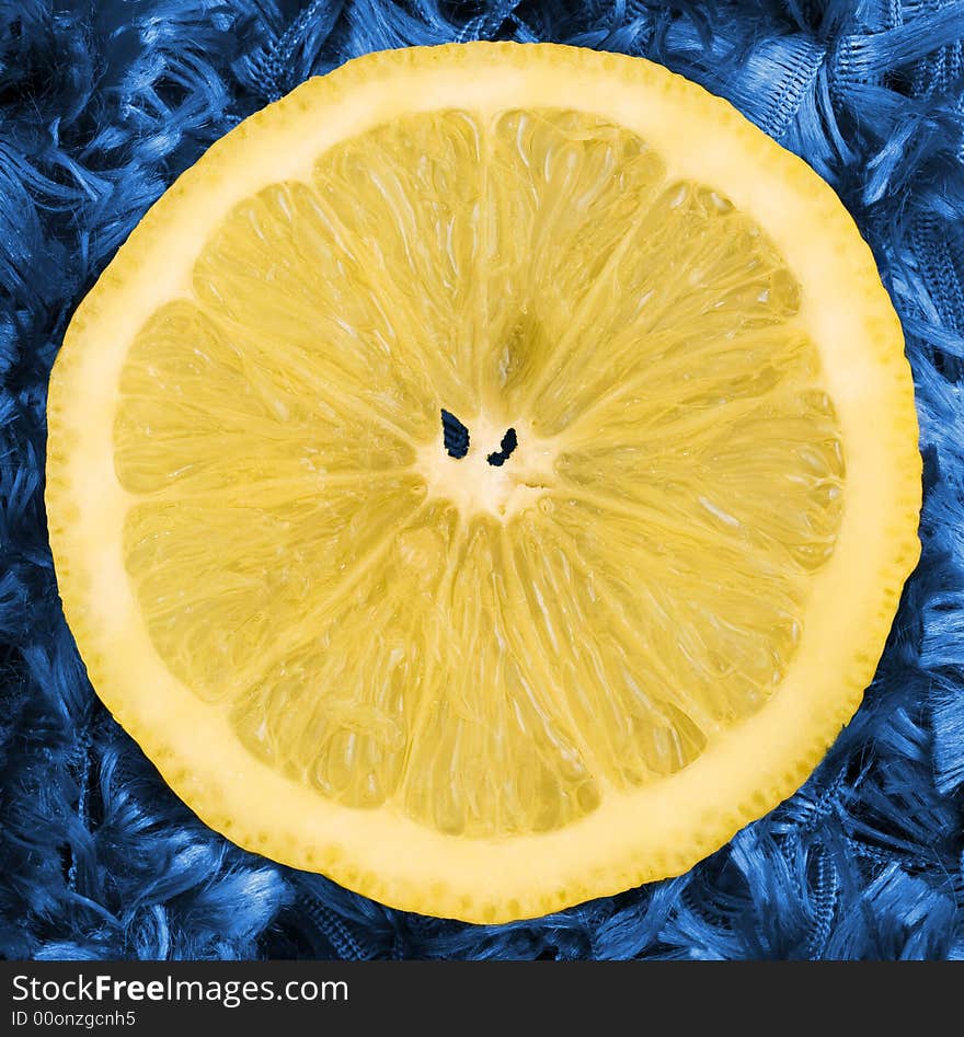 A juicy slice of lemon isolated on a blue background. A juicy slice of lemon isolated on a blue background.