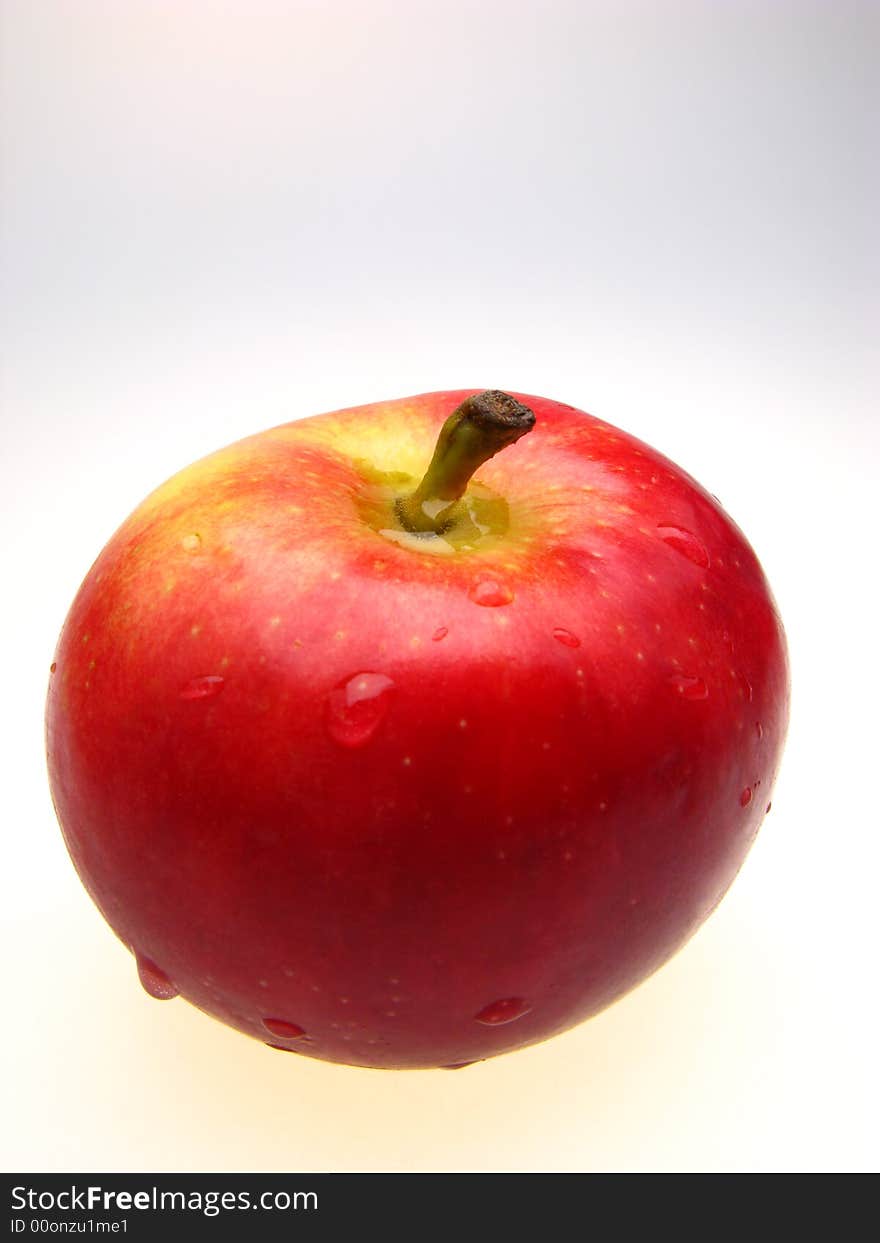 Red apple covered with drops of water on white background