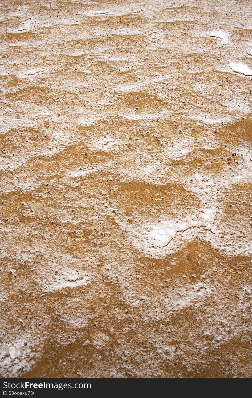 Sand covered by thin snow background in vertical