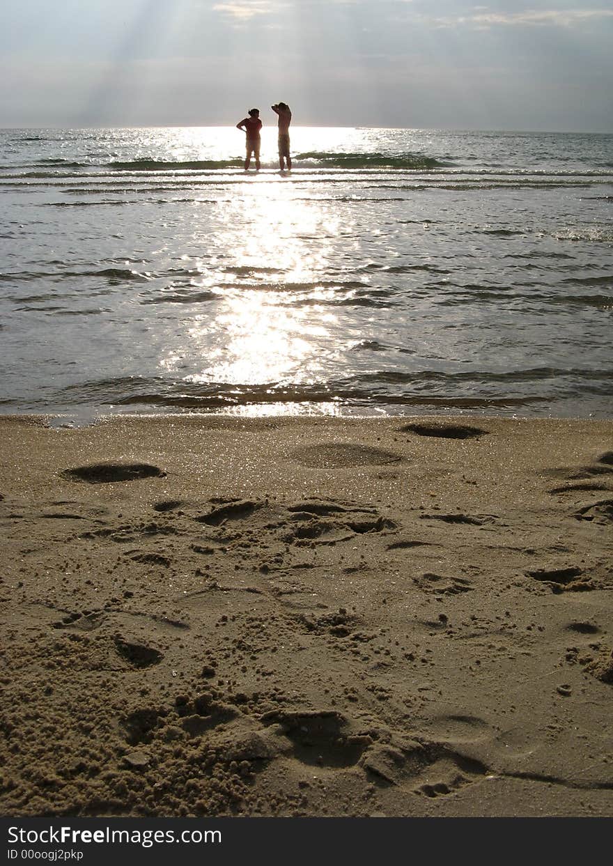 A man and woman standing in shallow water at the beach in the afternoon. A man and woman standing in shallow water at the beach in the afternoon