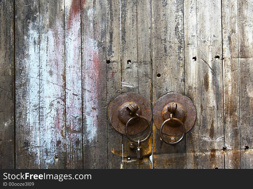 Rust knockers on the wooden door. A lock is on one of the ring. Rust knockers on the wooden door. A lock is on one of the ring.