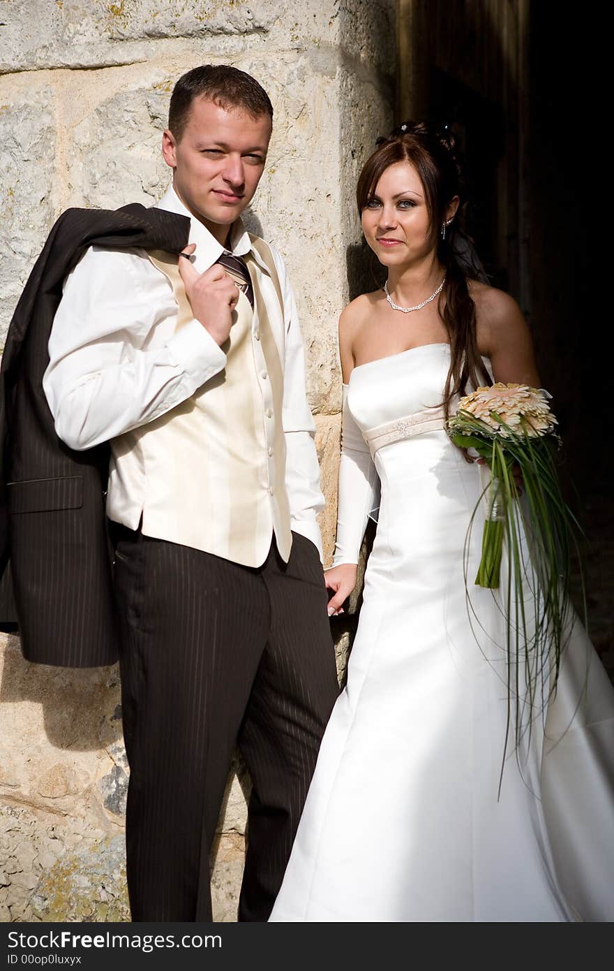 Bride and groom leaning on a wall holding their hands. Bride and groom leaning on a wall holding their hands.