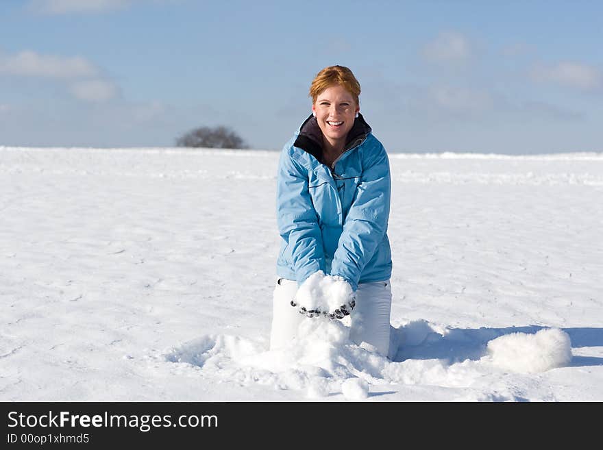 Nice woman kneeing in snow wanting to throw up a handful of snow. Nice woman kneeing in snow wanting to throw up a handful of snow