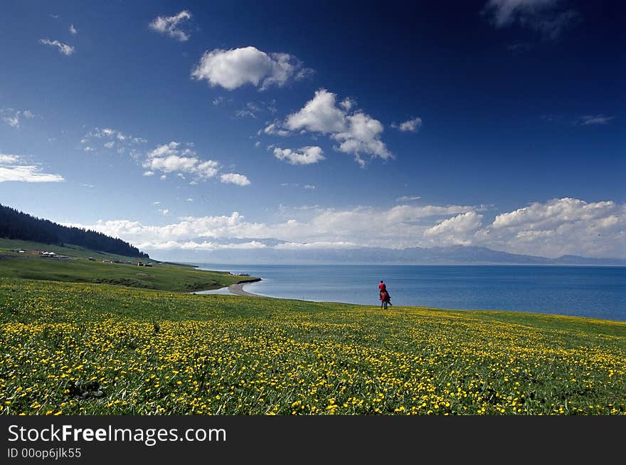 A Uigur rider is riding besides a very famous lake. The color of the lake is so blue which makes it look like sea. A Uigur rider is riding besides a very famous lake. The color of the lake is so blue which makes it look like sea.