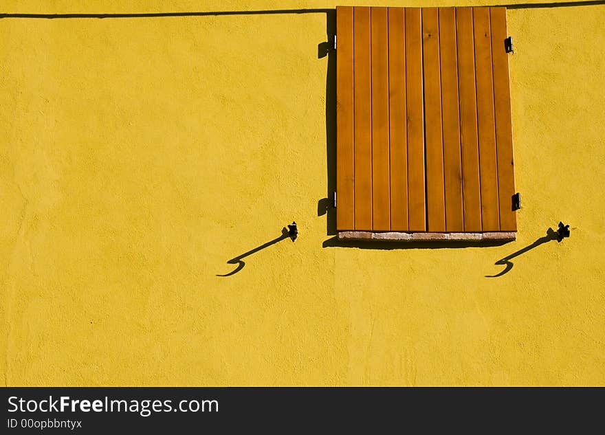 View of a wooden window on a yellow wall. View of a wooden window on a yellow wall