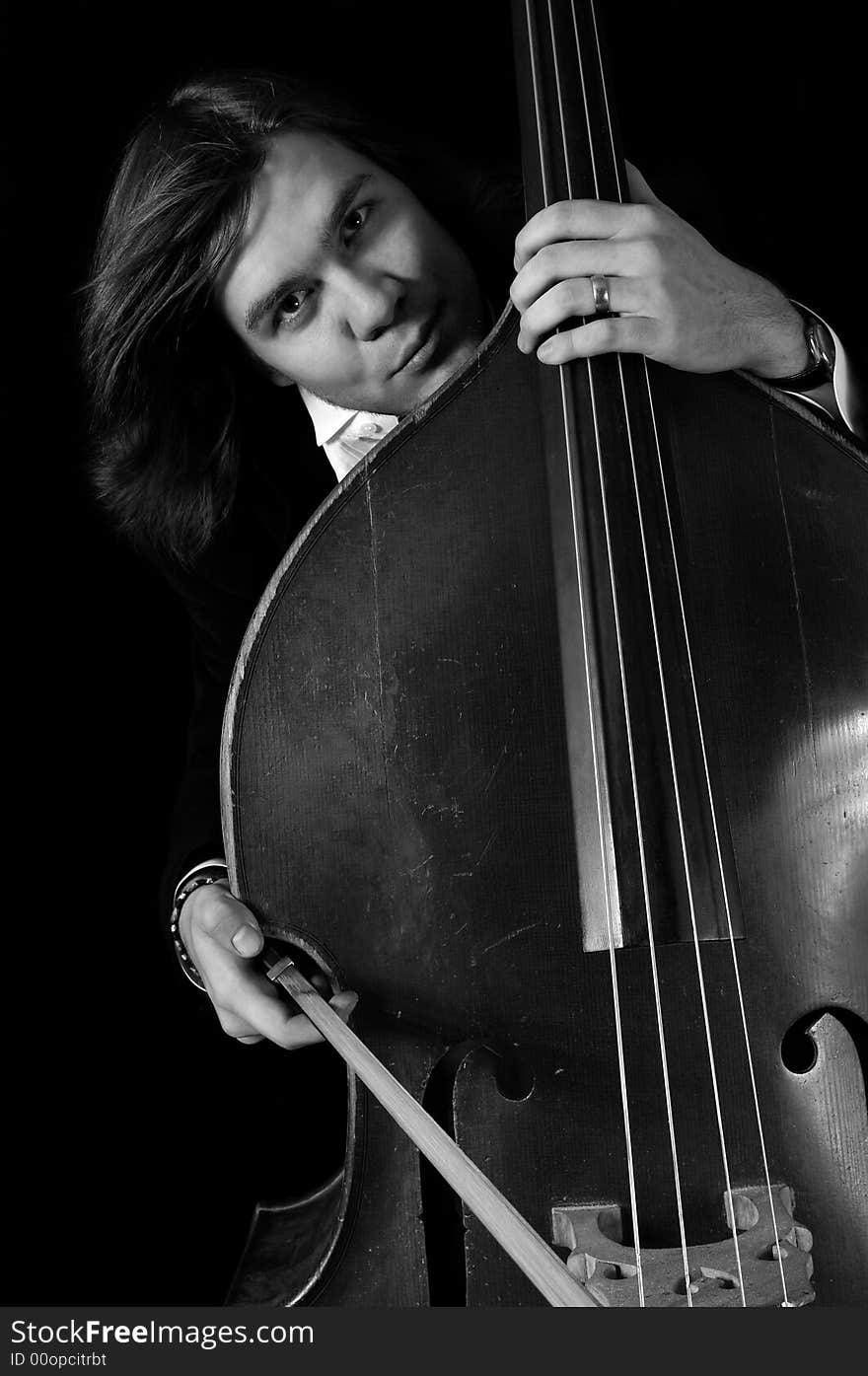 Melancholy musician with a contrabass over black background. bnw