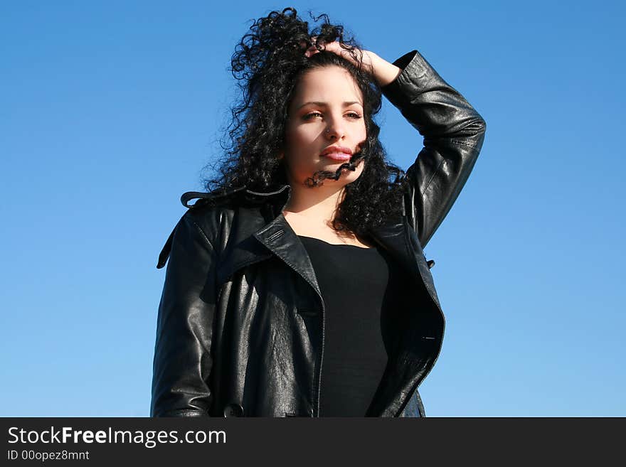 A young woman in leather jacket under the blue sky