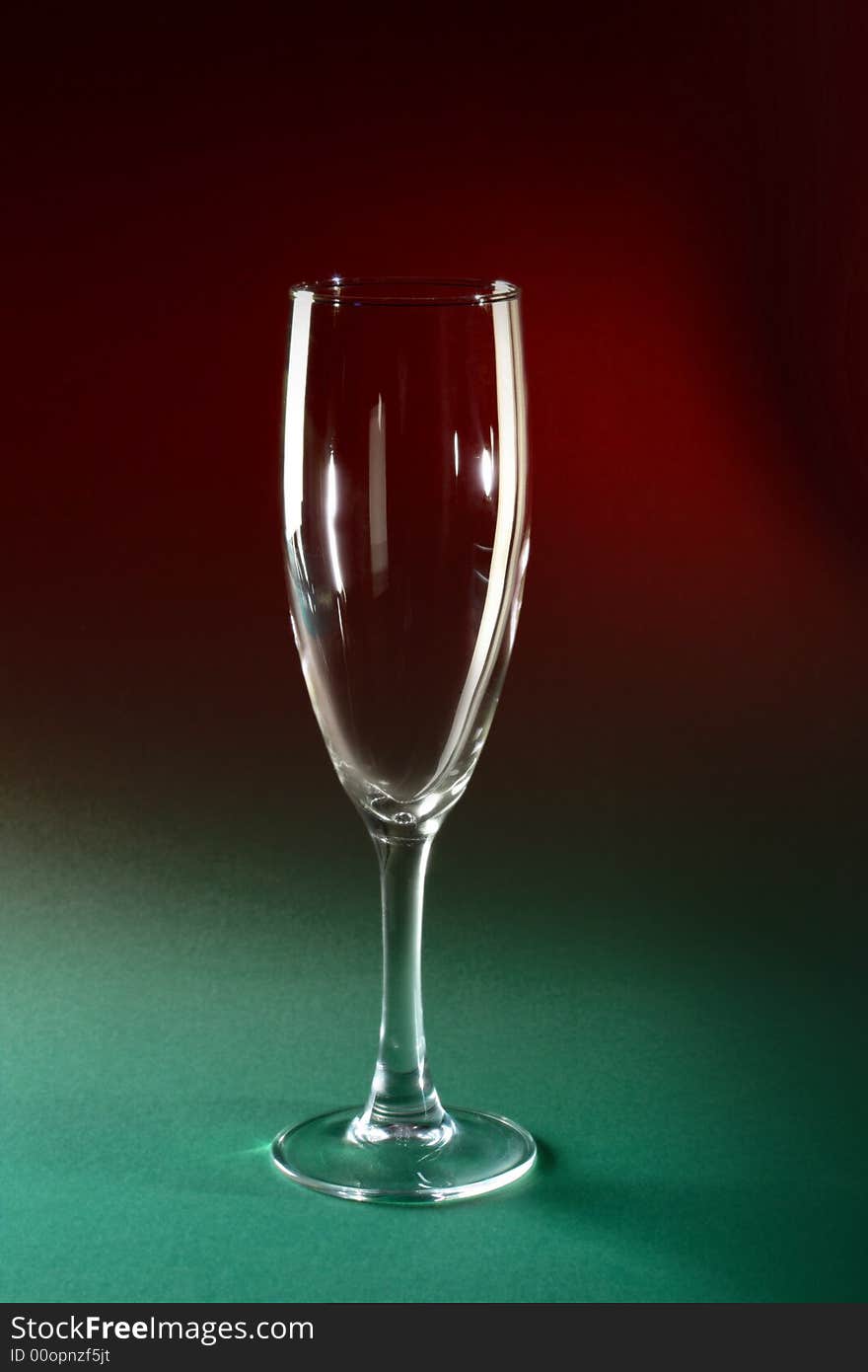 Single champagne glass on red and green background