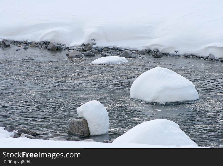 Rocks and river bank covered in freshly fallen winter powder. Rocks and river bank covered in freshly fallen winter powder