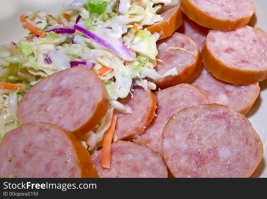 Sausage sliced with coleslaw in dish. Sausage sliced with coleslaw in dish