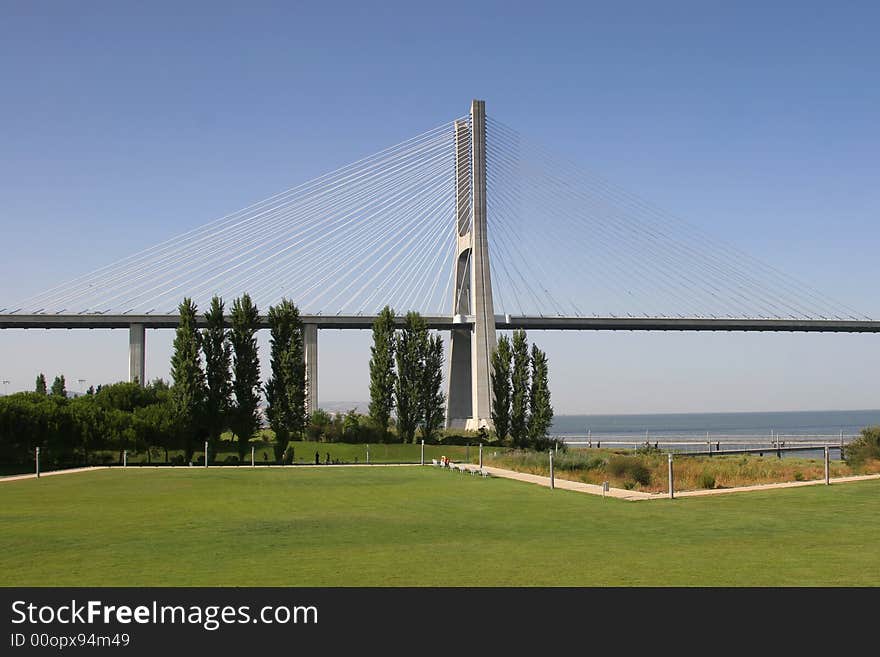 View of one of Lisbon's bridges with a grass lawn in foreground. View of one of Lisbon's bridges with a grass lawn in foreground