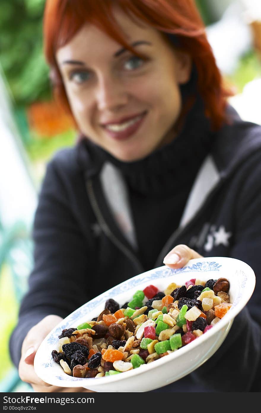 Young laughing red-haired woman offering candied fruits