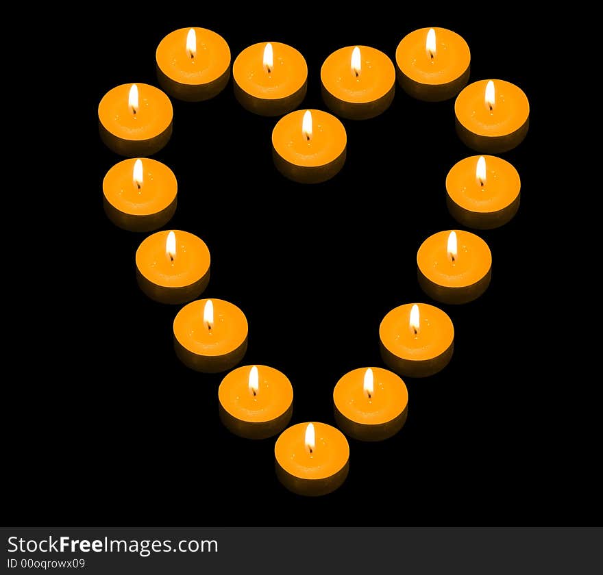 A group of burning candles forming a fiery heart on the black background. A group of burning candles forming a fiery heart on the black background