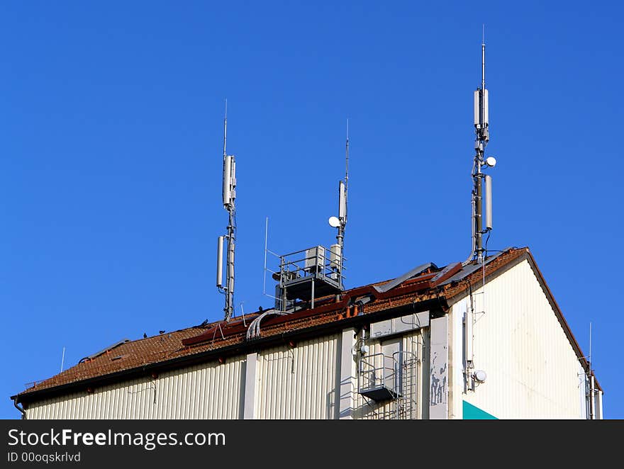 Anthenne group at the tile roof of industrial building at the background of blue sky . Connection wires and small iron trap . Anthenne group at the tile roof of industrial building at the background of blue sky . Connection wires and small iron trap .