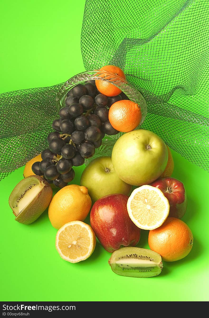 Rich assortment of fruit consisting of apples, citron, grapes, kiwi on a green background