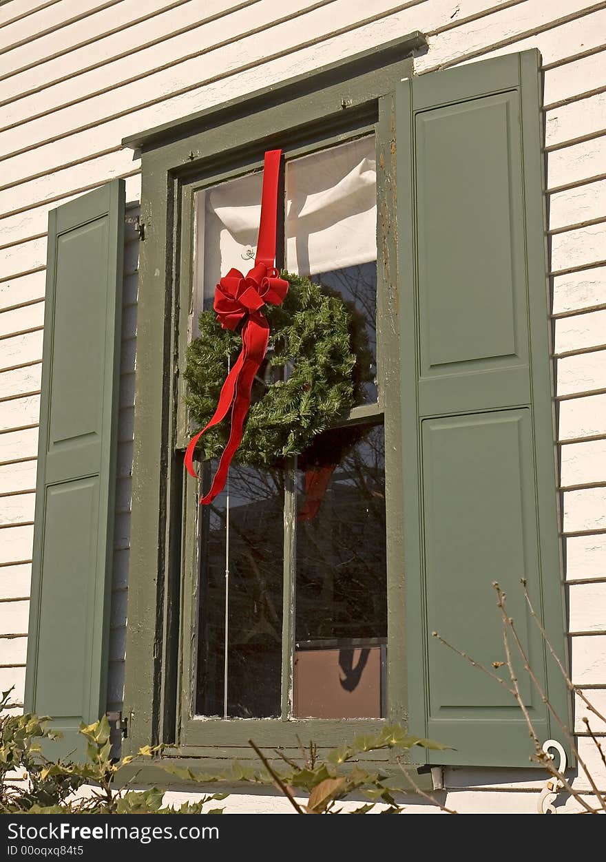 A window on an old house decorated with a wreath for Christmas. A window on an old house decorated with a wreath for Christmas