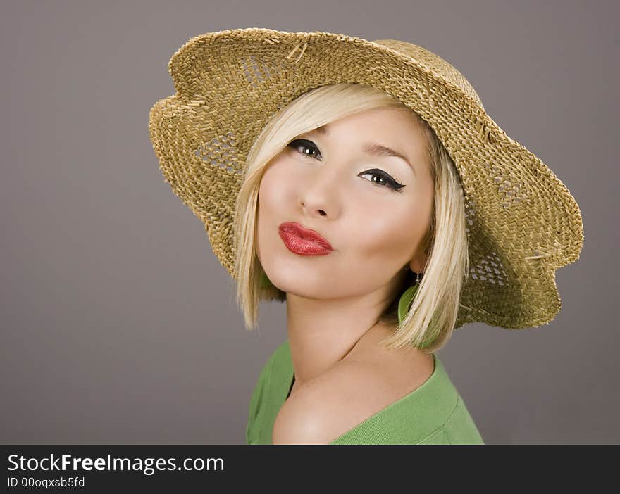 A fresh young blonde model in a straw hat puckering for the camera. A fresh young blonde model in a straw hat puckering for the camera