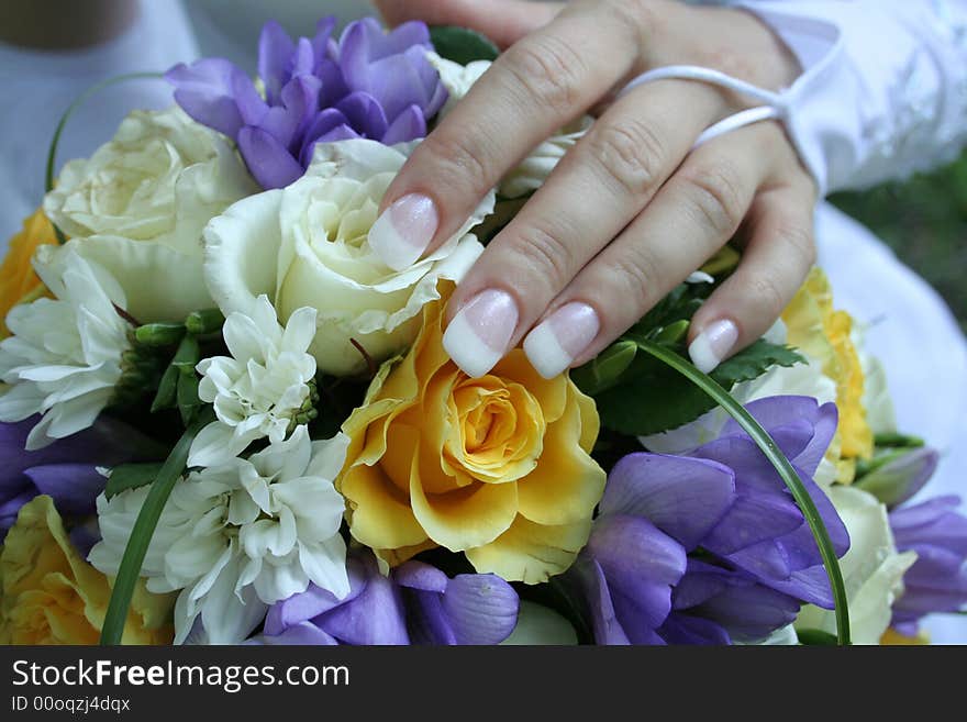 The gentle hand of the bride lays on a bouquet