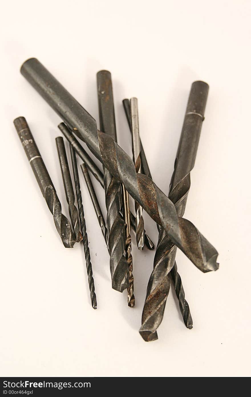 Many drill bits of different sizes on white background