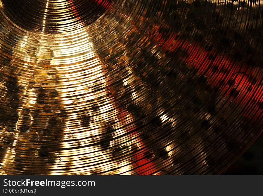 Detail of brass cymbal with red light reflections. Detail of brass cymbal with red light reflections