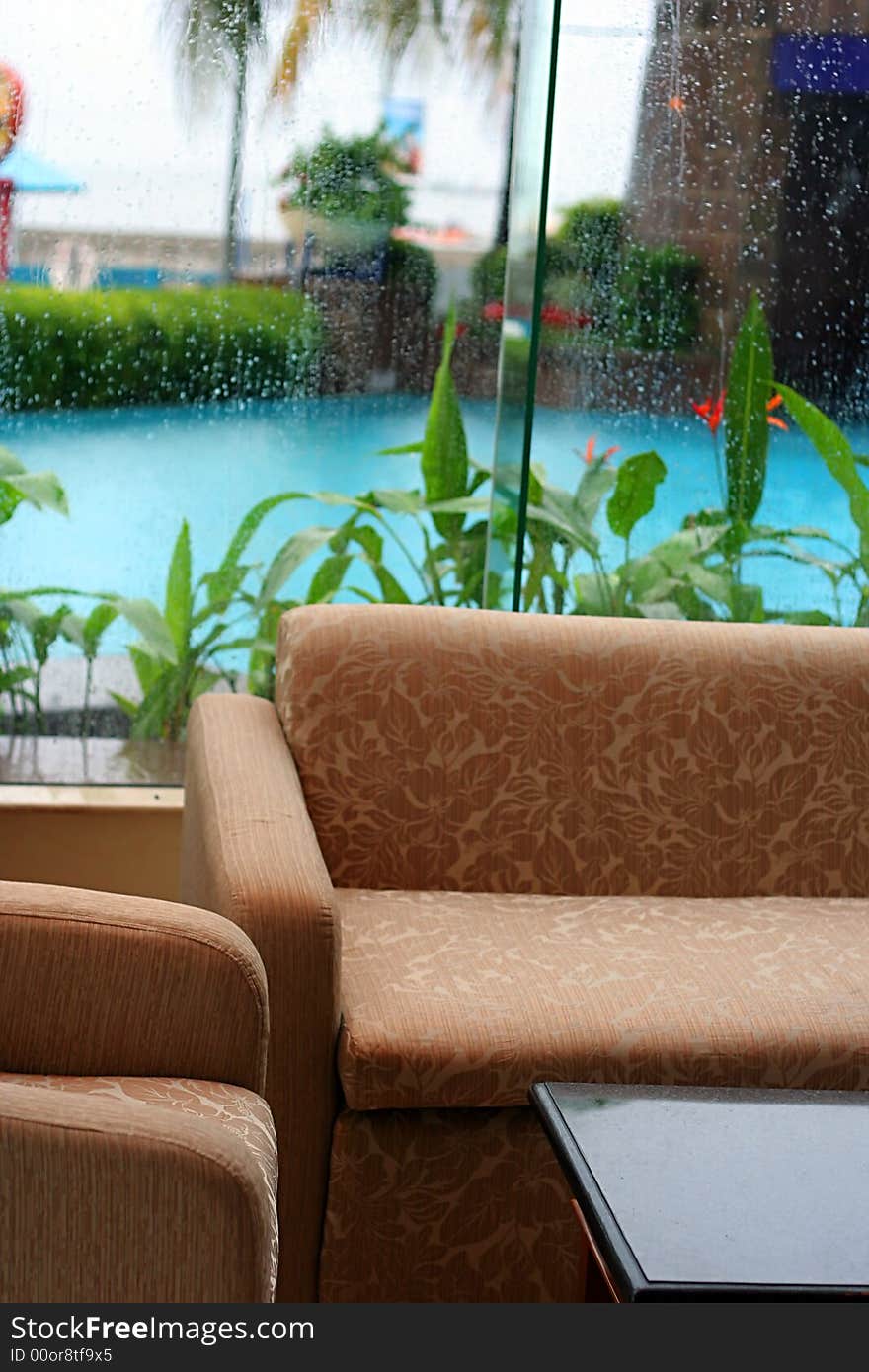 Sofa near by pool and window glass in rainy day