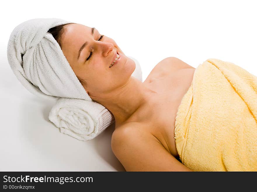 Woman from upper sideview. Lying on neck support, wrapped into bath towel. Woman from upper sideview. Lying on neck support, wrapped into bath towel