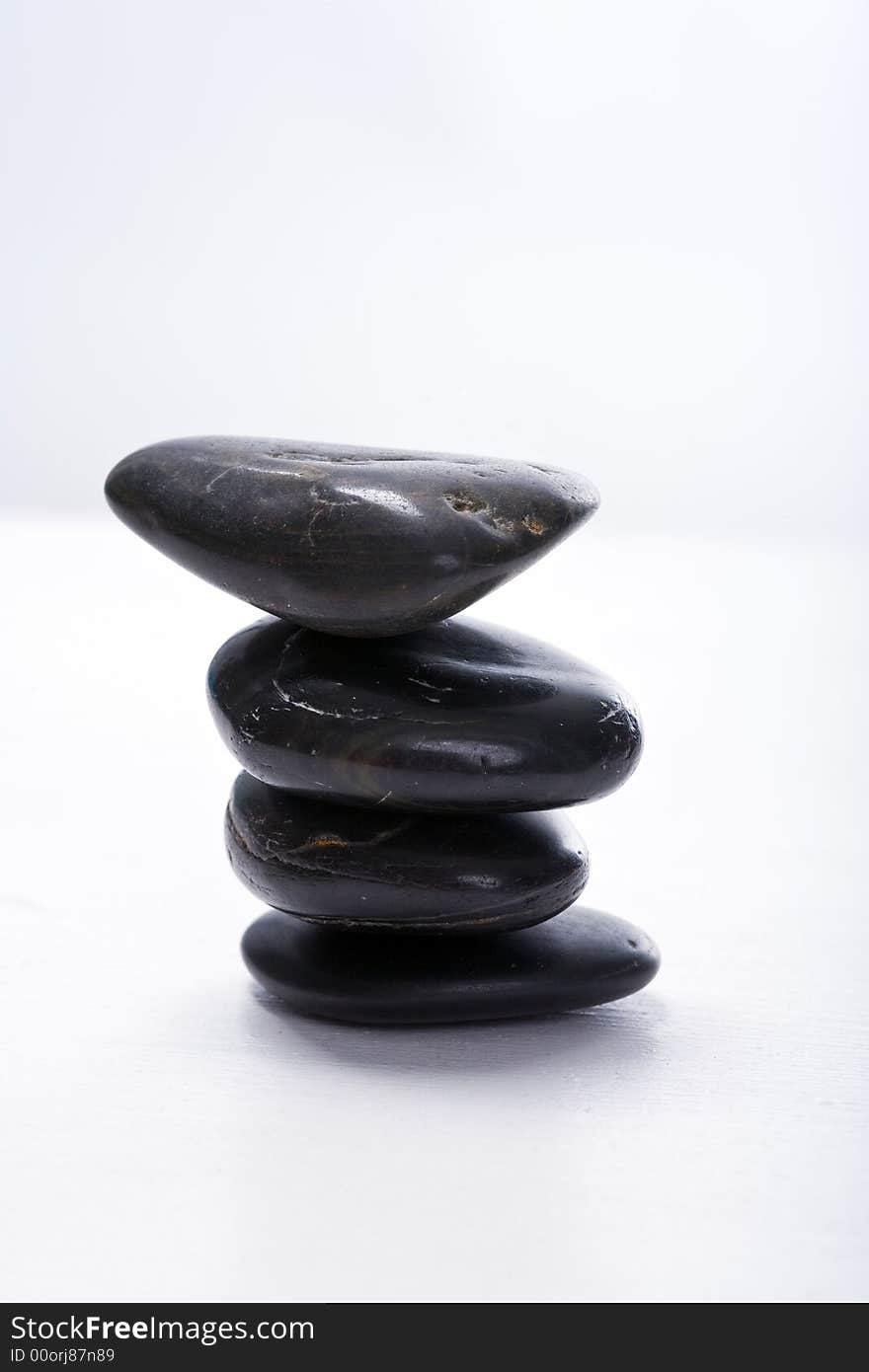 Four stapled, round, smooth black stones. Zen-Style. White background. Reassuring. Four stapled, round, smooth black stones. Zen-Style. White background. Reassuring.