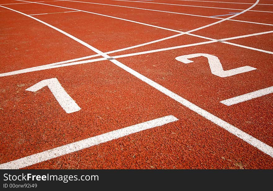 First two numbers of a racetrack, on red tarmac, for runners. First two numbers of a racetrack, on red tarmac, for runners