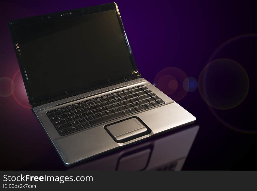 Laptop with refections and lens flare on a table. Laptop with refections and lens flare on a table