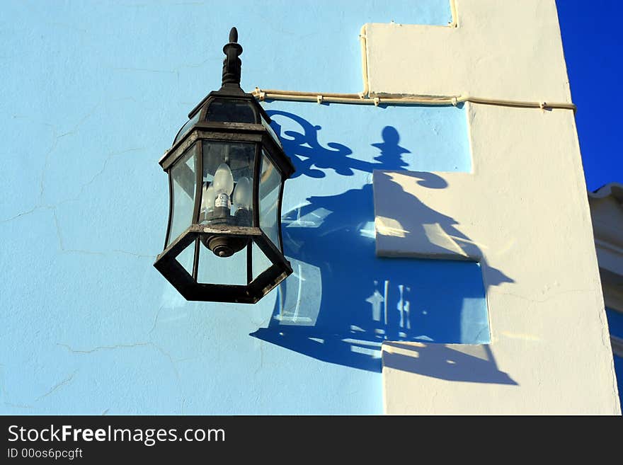 Black iron lantern hanging on a blue and white wall