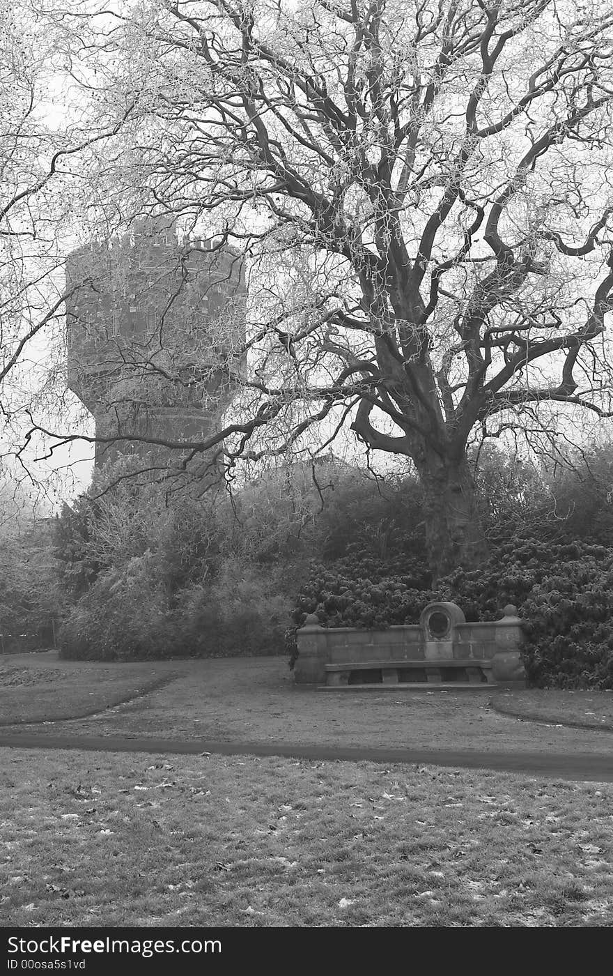 Stone bench in a park in winter, water tower in the background, vlack and white. Stone bench in a park in winter, water tower in the background, vlack and white