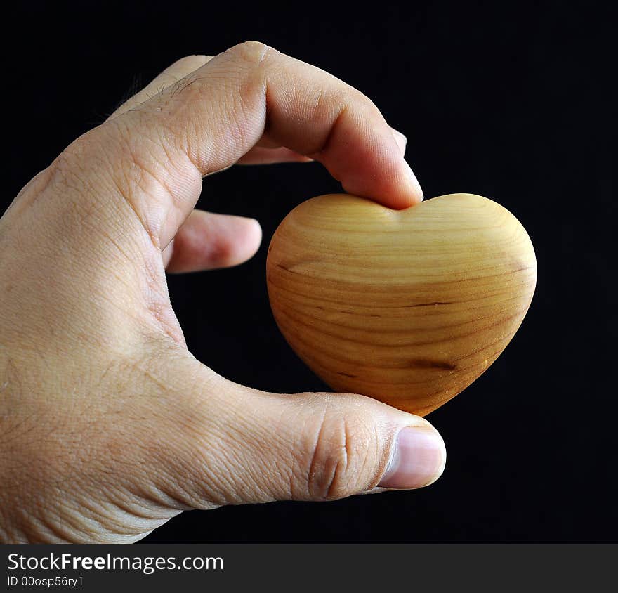 Man's hand holding a heart against black background