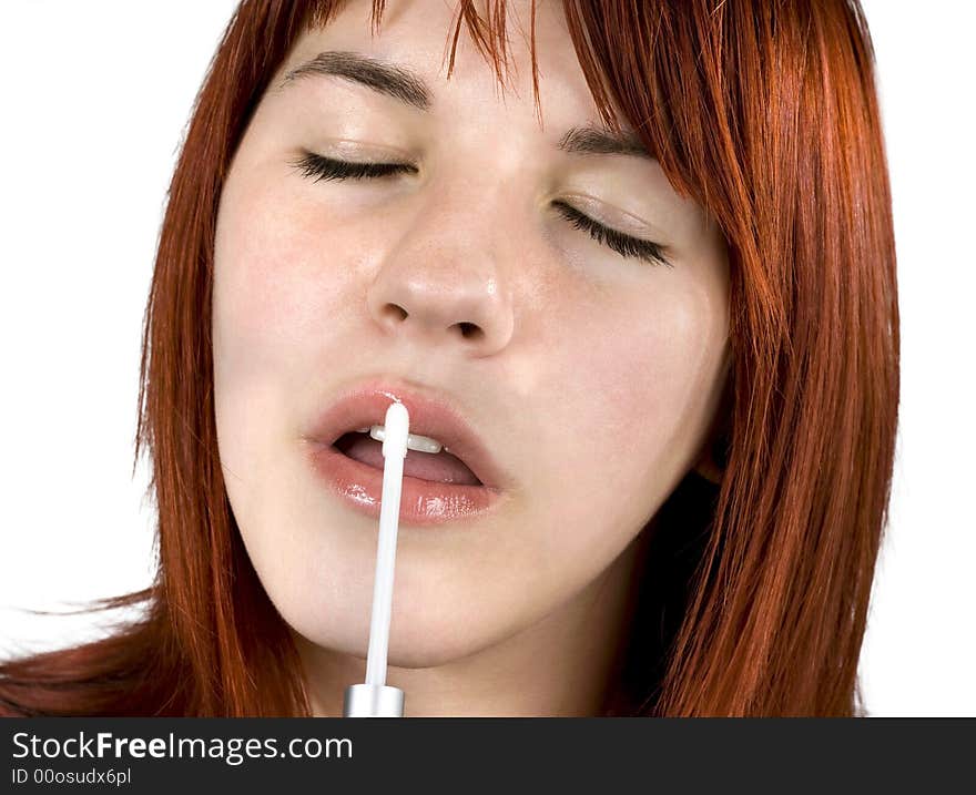 Cute redhead girl (close-up portrait) applying a shiny lipstick to her lips. Cute redhead girl (close-up portrait) applying a shiny lipstick to her lips.