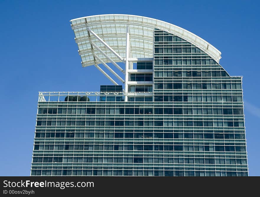 A modern blue glass office tower with a white curved roof. A modern blue glass office tower with a white curved roof