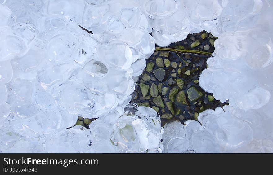 Iced water melting away showing stones. Iced water melting away showing stones