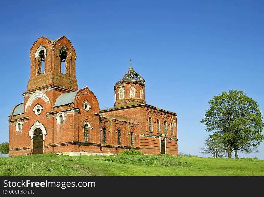 The destroyed orthodox church costs on a hill in the neighbourhood with an oak. The destroyed orthodox church costs on a hill in the neighbourhood with an oak