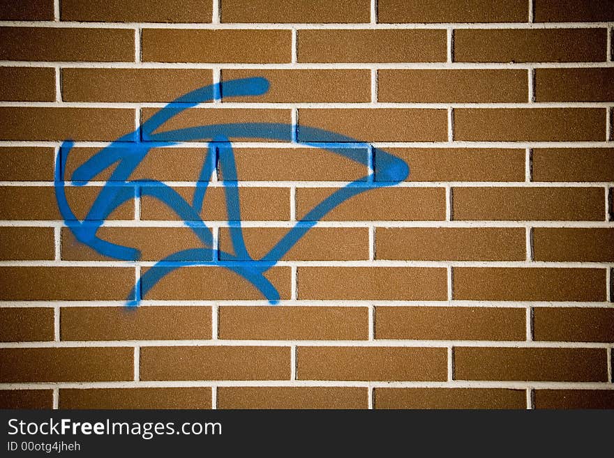 Photo of a plain red brick wall with a blue graffito. Photo of a plain red brick wall with a blue graffito