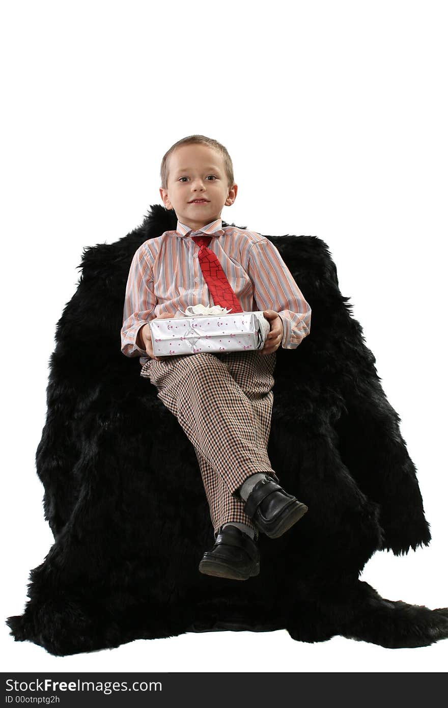 The boy holds in hands a gift, sitting in a soft armchair. The boy holds in hands a gift, sitting in a soft armchair