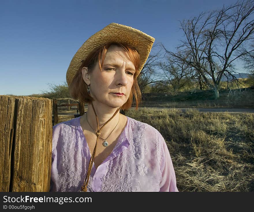 Portrait of a woman in a purple shirt and cowboy hat on a ranch. Portrait of a woman in a purple shirt and cowboy hat on a ranch.