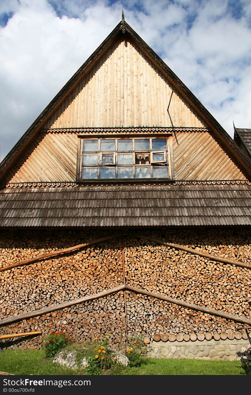 Pediment of the wooden house with the prepared fire wood for the winter