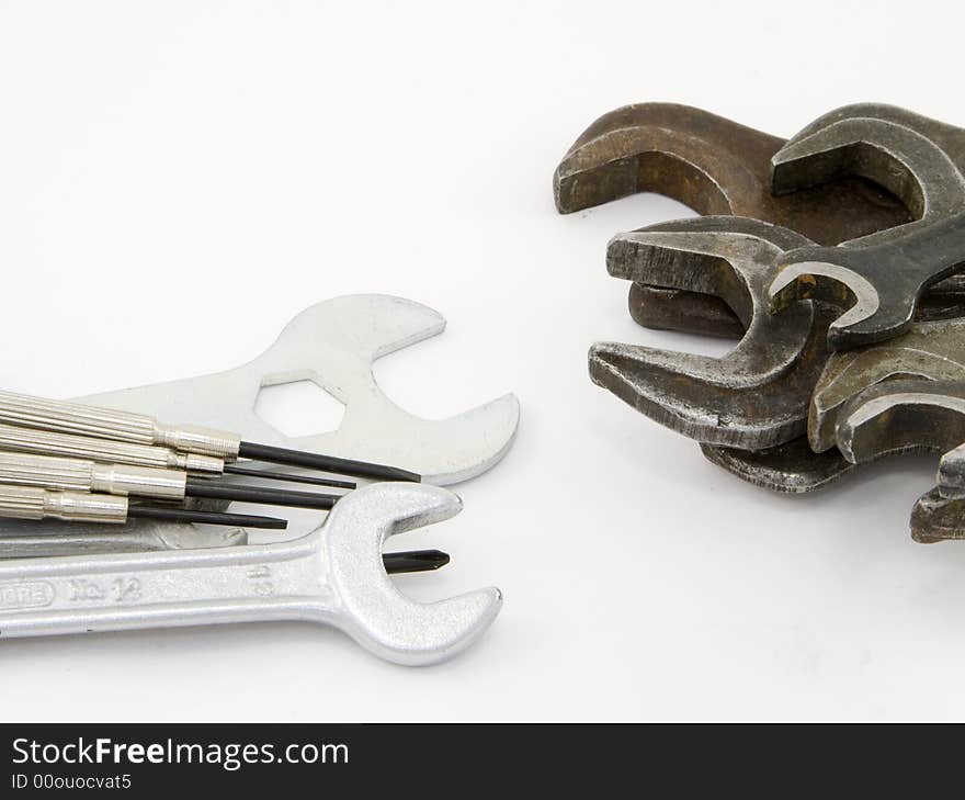 Wrenches and screw-drivers of different colors laying on a white background